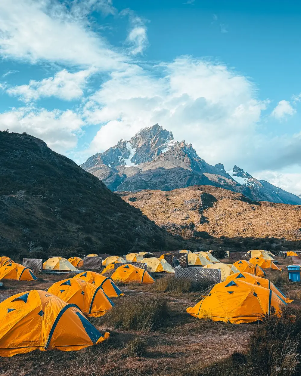 Yellow tents in a mountain camp below a granite peak